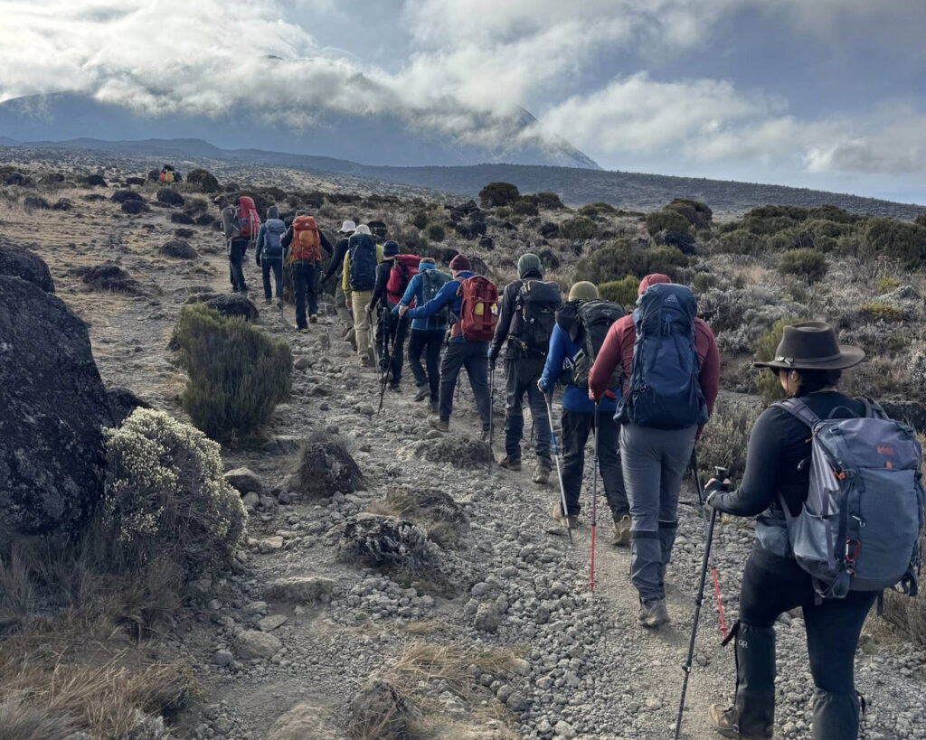 Climbers ascending a steep rocky incline on Mount Kilimanjaro – illustrating how hard is to climb Mount Kilimanjaro physically