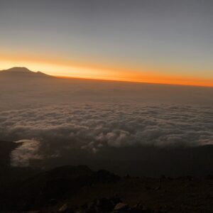 Sunrise from Mount Meru summit with Mount Kilimanjaro silhouetted above a sea of clouds, Arusha National Park, Tanzania