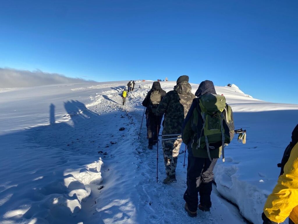 Kilimanjaro Climbing Costs 2026 hikers trekking up Mount Kilimanjaro route through scenic mountain trail during ascent in Tanzania