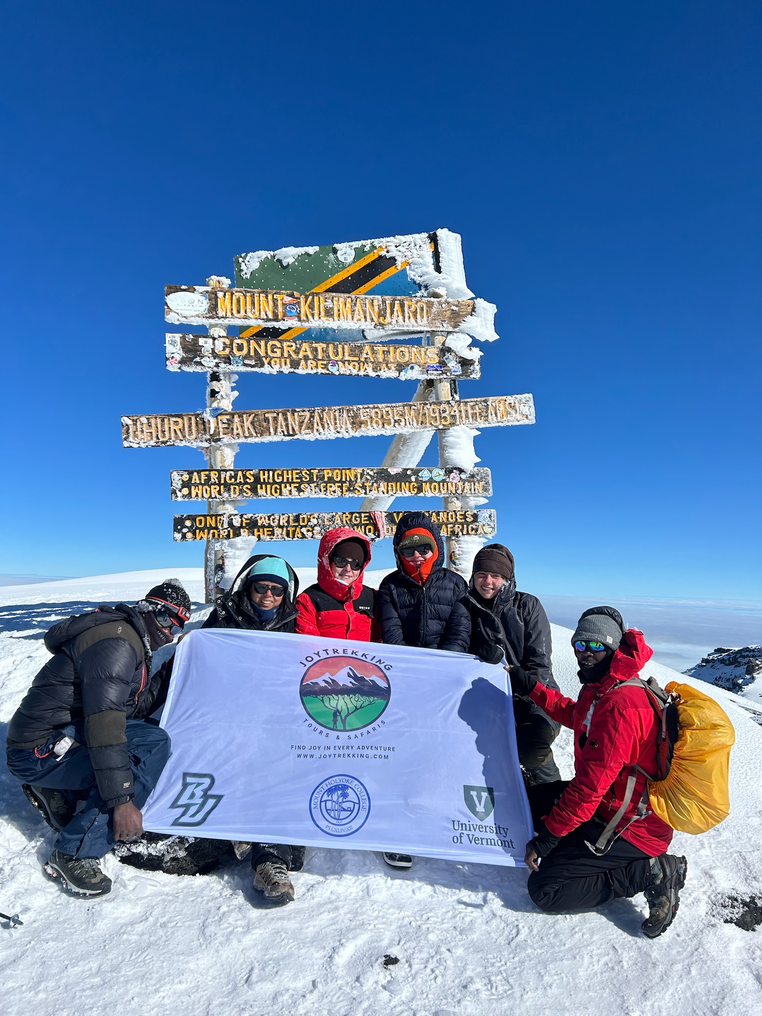 Group of climbers celebrating at Uhuru Peak on Mount Kilimanjaro after a successful summit using the right Mount Kilimanjaro Packing List for extreme high-altitude trekking