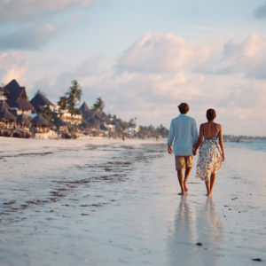Couple walking along a quiet beach in Zanzibar at sunset