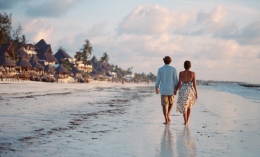 Couple walking along a quiet beach in Zanzibar at sunset