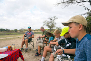 Family enjoying breakfast during a morning safari in Selous Game Reserve illustrating the minimum age for walking safari in Tanzania