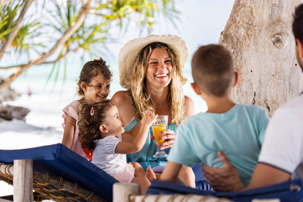 Happy parents and kids enjoying a Tanzania Family Vacation on the beach, relaxing on deck chairs and having fun in the sun