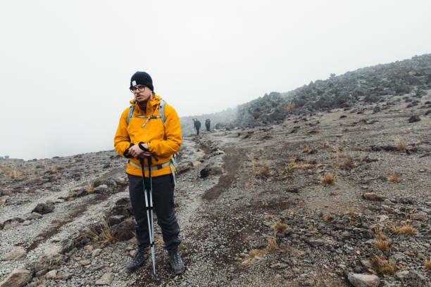 Man hiker wearing layered clothing with backpack hiking on a foggy mountain trail on Mount Kilimanjaro, demonstrating essential clothing from a Mount Kilimanjaro Packing List