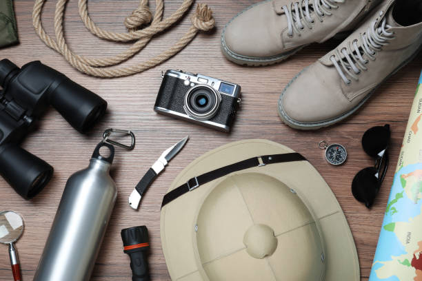 Flat lay of Tanzania safari travel accessories including binoculars camera hat map and backpack on wooden background