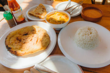 Unique Foods in Zanzibar served on a traditional table with rice, pizza, chapati and chicken curry