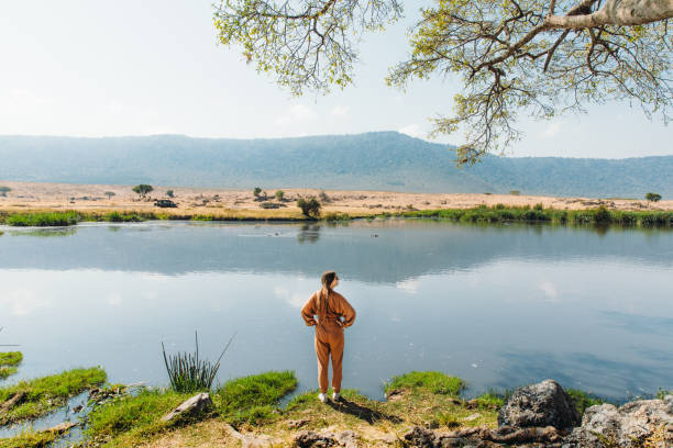 Solo female traveler standing near a crater lake in Ngorongoro Conservation Area, Tanzania, enjoying the scenic view