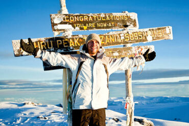 How Difficult Is It to Climb Mount Kilimanjaro? Happy climber celebrating at Uhuru Peak summit