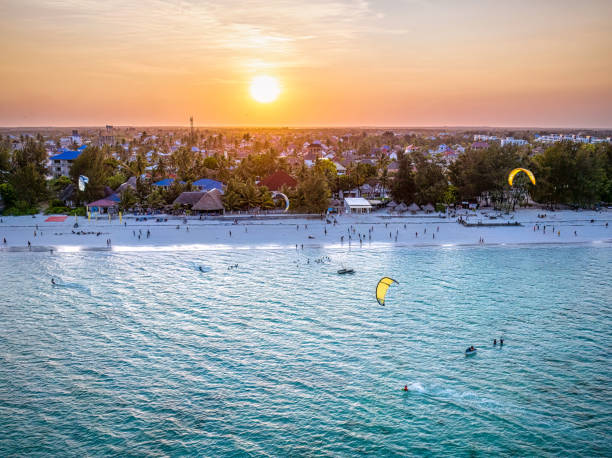 Tourists kitesurfing in the ocean at sunset in Paje Beach Zanzibar showing the best time to visit Zanzibar for the best weather