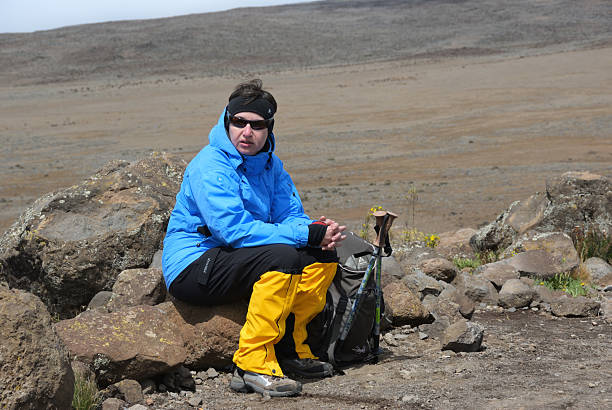 Tired woman climber taking a short rest on Mount Kilimanjaro during adventure activities in Tanzania
