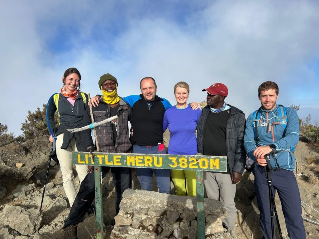 International trekkers celebrating at Little Meru Peak in Arusha National Park Tanzania