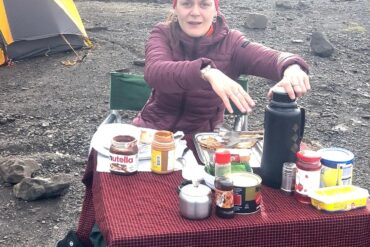 French climber Pauline having breakfast at Shira Cave Camp on Mount Kilimanjaro, enjoying high-energy food as part of what to eat and drink on Mount Kilimanjaro for altitude performance.
