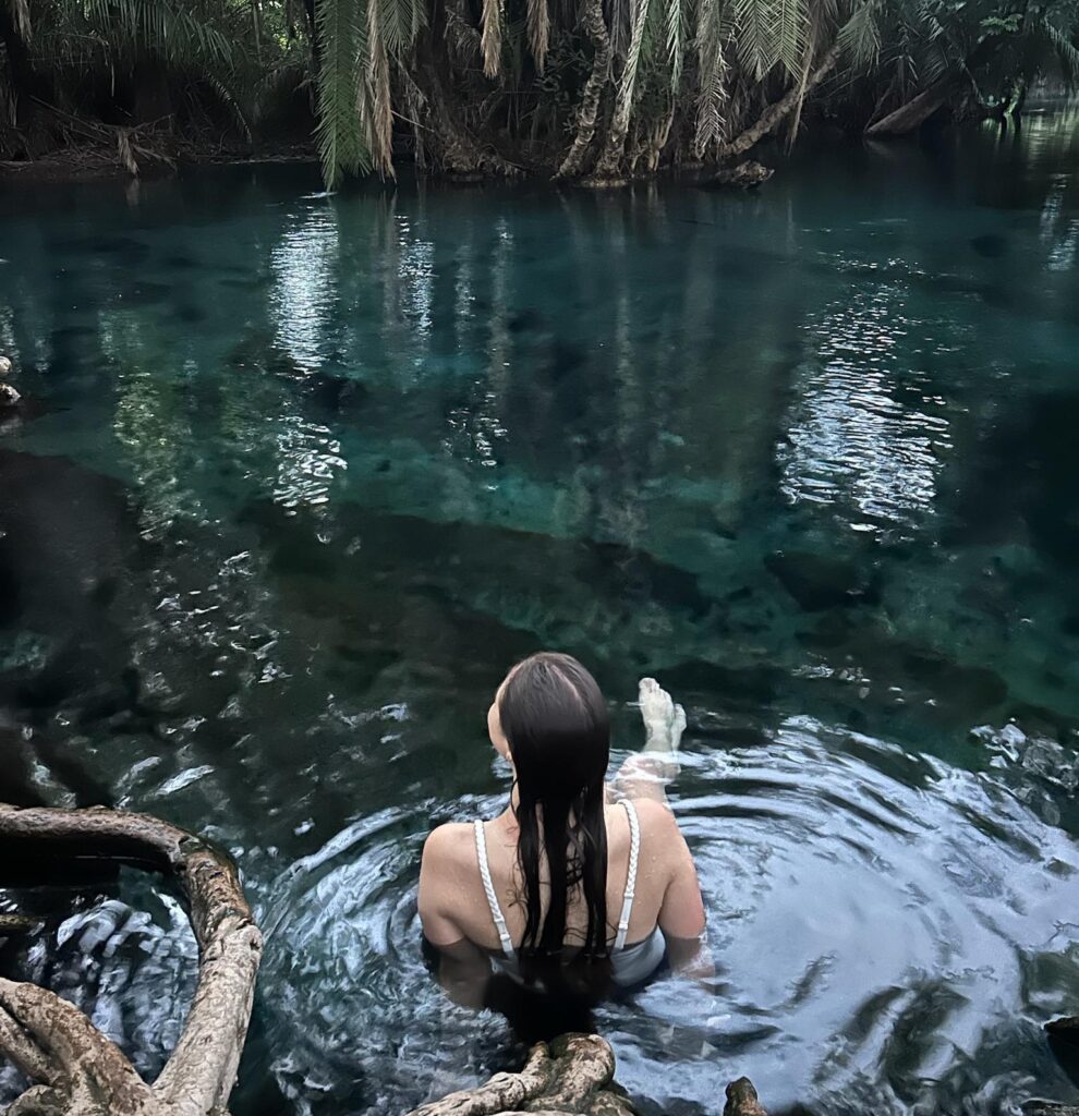 Female traveler enjoying a swim in the crystal-clear waters of Chemka Hot Springs during a Chemka Hot Springs day trip from Moshi in Northern Tanzania.