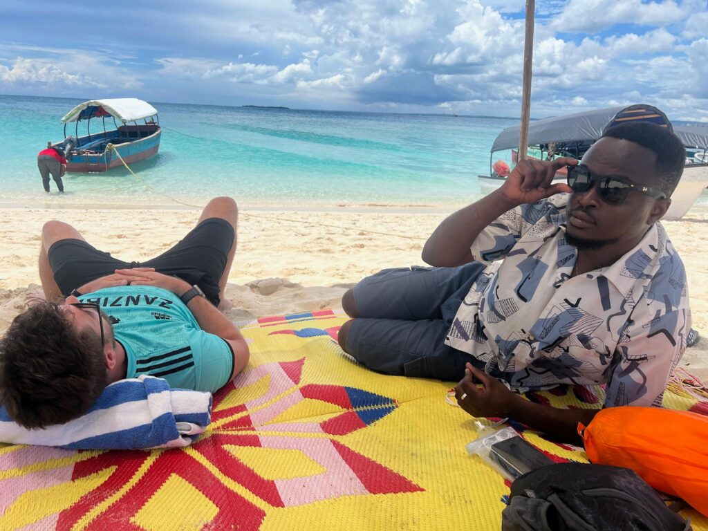 Tour guide with tourists relaxing on soft white sand at Paje Beach Zanzibar showcasing adventure and deep relaxation experience in Tanzania
