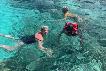 Scuba Diving in Tanzania January and Travellers with scuba mask and snorkel standing in crystal clear sea looking at a starfish
