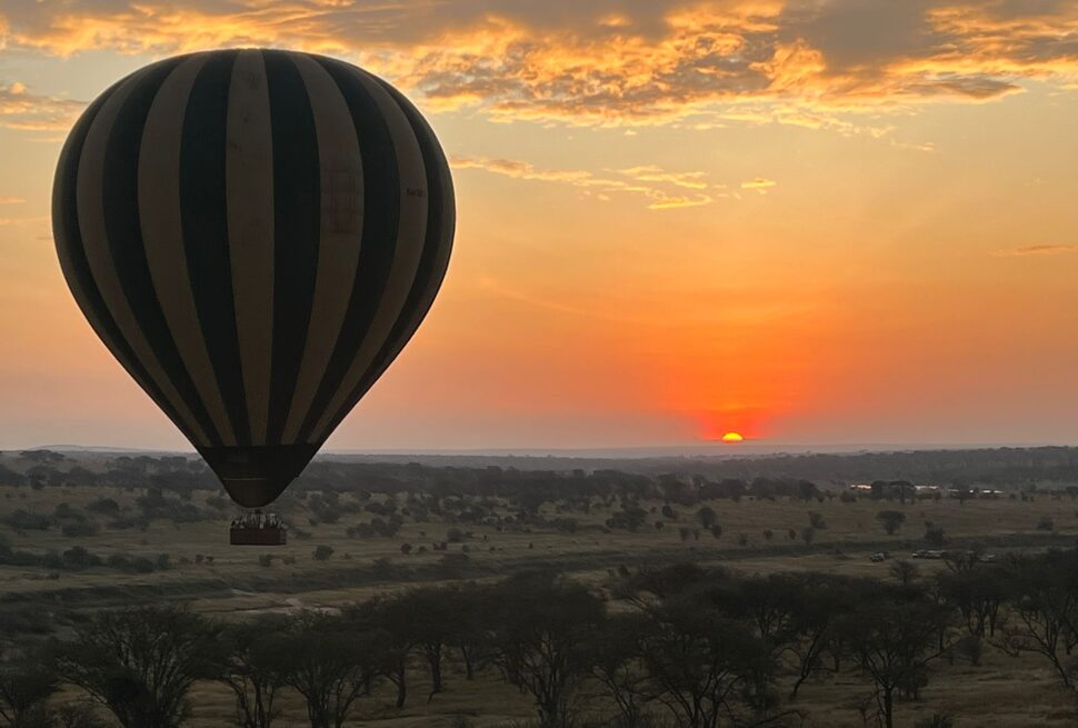 Hot air balloon safari in Serengeti floating above Serengeti National Park at sunrise with golden savannah views and soft morning light