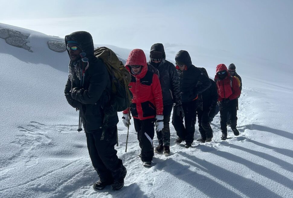 How many days to climb Mount Kilimanjaro — trekkers hiking through the snowy summit trail near Uhuru Peak in Tanzania