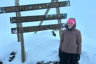 Pauline standing at Uhuru Peak on Mount Kilimanjaro covered in snow after summit, showing achievement despite altitude sickness Altitude Sickness on Mount Kilimanjaro challenges