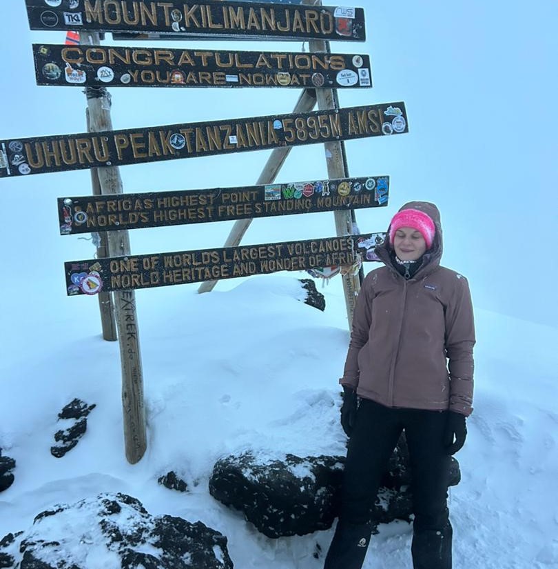 Pauline standing at Uhuru Peak on Mount Kilimanjaro covered in snow after summit, showing achievement despite altitude sickness Altitude Sickness on Mount Kilimanjaro challenges