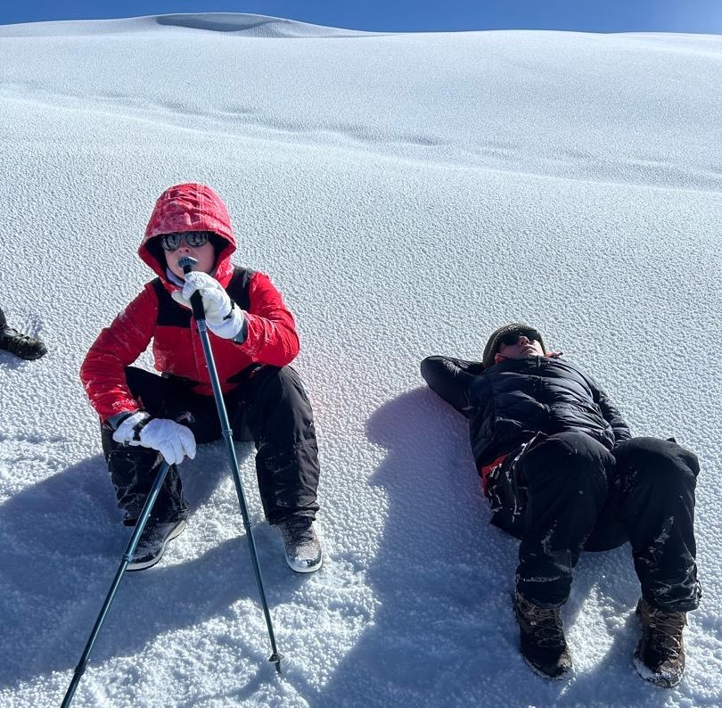 Two female climbers resting inside sleeping bags at high altitude camp on Mount Kilimanjaro, illustrating sleep and recovery challenges during summit trek and altitude adaptation