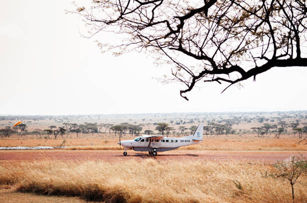 Cessna single-engine aircraft landing on a dusty airstrip during a Tanzania Fly-In Safari Tour in Serengeti Grumeti Reserve, Tanzania.