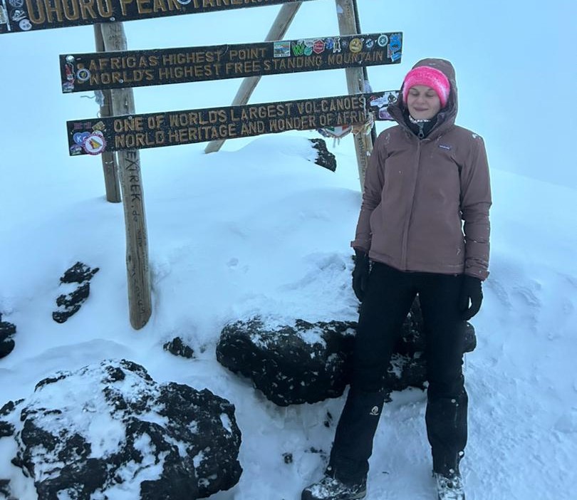 Climber standing at Uhuru Peak on Mount Kilimanjaro celebrating summit success during Affordable Kilimanjaro Climbing Packages 2026