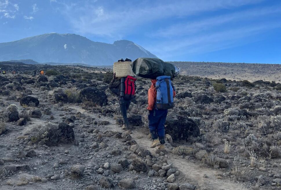 Porters trekking on Mount Kilimanjaro routes during ascent through mountain trails