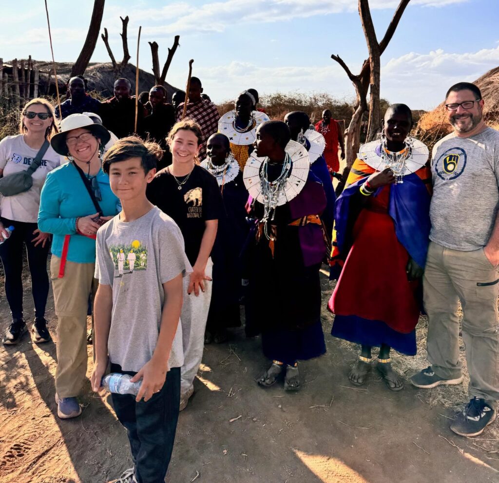 International travelers experiencing Maasai culture in a traditional village during a Tanzania Local Experience Guide tour