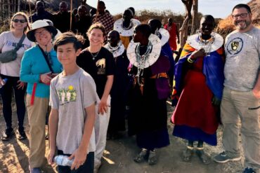 International travelers experiencing Maasai culture in a traditional village during a Tanzania Local Experience Guide tour