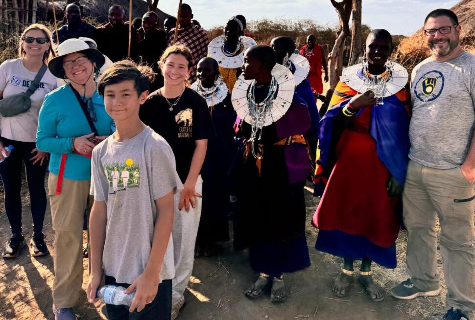 International travelers experiencing Maasai culture in a traditional village during a Tanzania Local Experience Guide tour