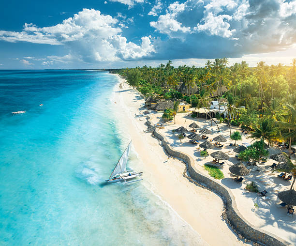Best Time for Tanzania Safari and Zanzibar beach holiday aerial view of sailboat blue sea and white sandy beach at sunset