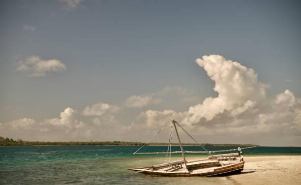 Scuba Diving in Tanzania Mafia Island coastal landscape showing a dhow boat ashore on the beach with sea, sky, clouds, and sand