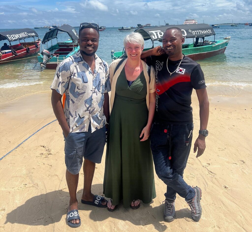 Affordable Tanzania Safari and Zanzibar Packages: guided travel experience in Pemba Island showing international visitors exploring the coastline with a local guide, traditional boats, and Indian Ocean views
