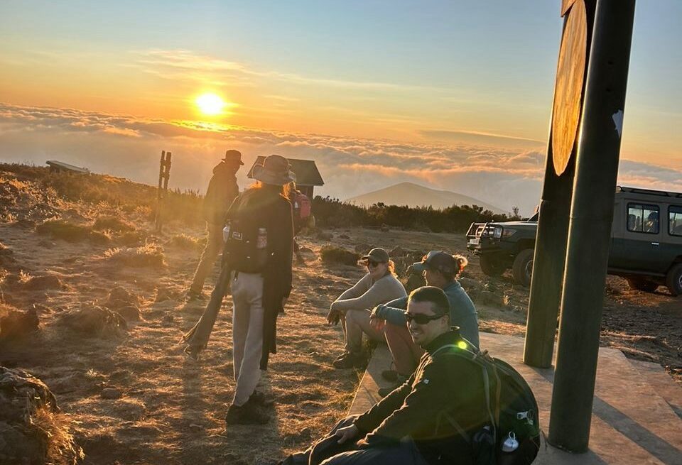 Tourists sitting on the ground and listening to their guide during a Kilimanjaro pre-climb briefing on how to prepare mentally for Kilimanjaro trek.