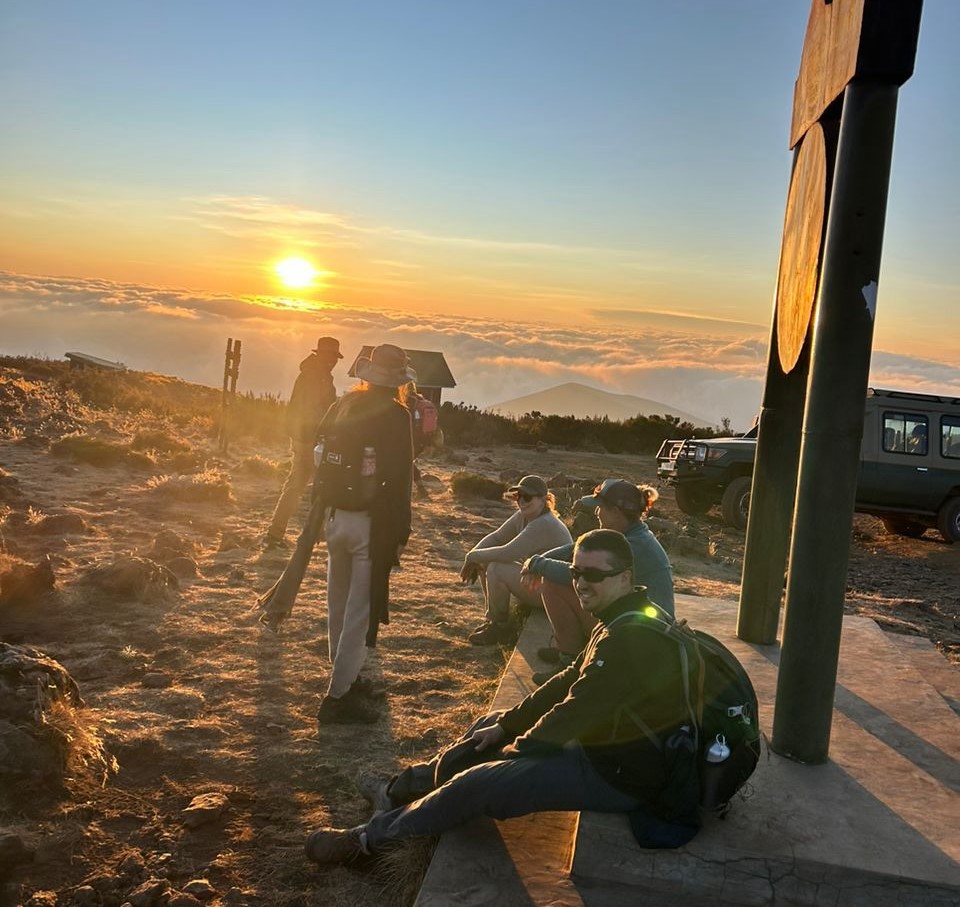Tourists sitting on the ground and listening to their guide during a Kilimanjaro pre-climb briefing on how to prepare mentally for Kilimanjaro trek.