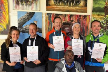 Best Tanzania travel experts Kilimanjaro summit success group of climbers celebrating after reaching Uhuru Peak with certificates