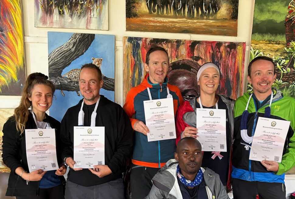 Best Tanzania travel experts Kilimanjaro summit success group of climbers celebrating after reaching Uhuru Peak with certificates