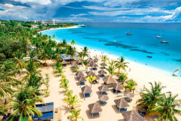 Aerial view of white sandy beach in Kendwa, Zanzibar with palm trees, yachts, and clear blue ocean at sunset, representing Zanzibar vacation cost and luxury tropical holiday experience.