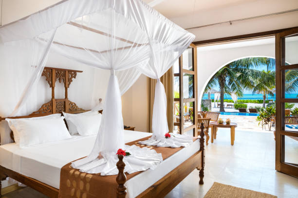 Luxury Zanzibar vacation accommodation featuring a double bed with mosquito net in a modern holiday villa bedroom, reflecting Zanzibar vacation cost for mid-range and luxury stays.
