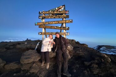 Kilimanjaro Climbing Fees guide showing a happy couple celebrating at Uhuru Peak summit in Tanzania