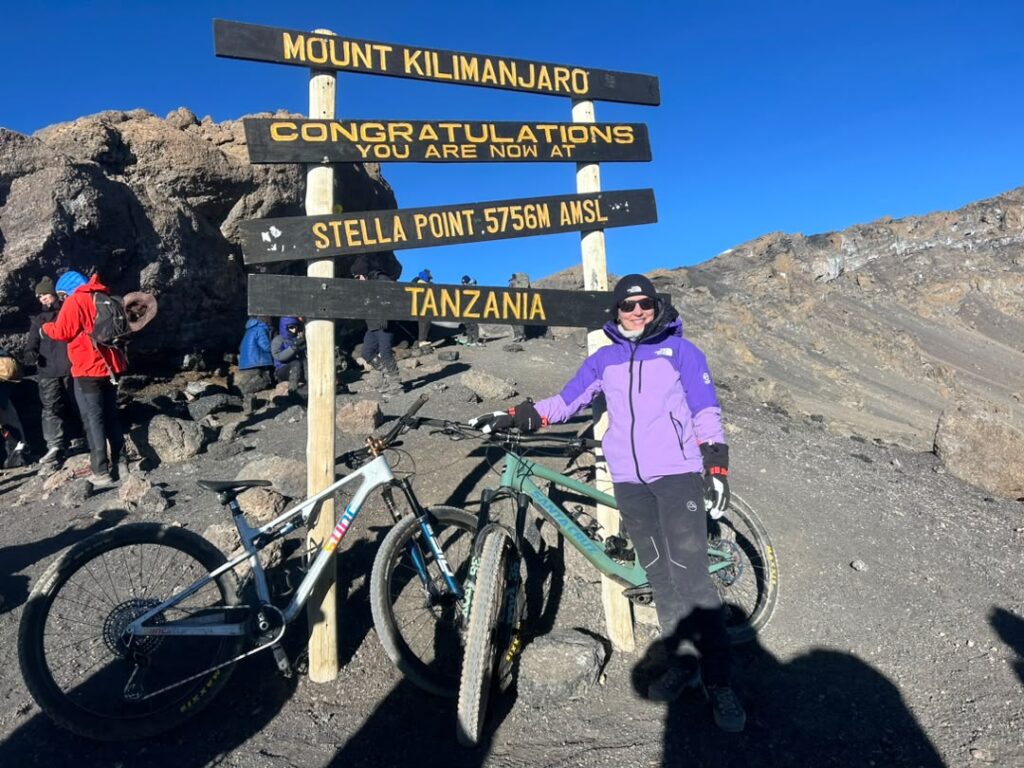 Kilimanjaro Luxury Climb Cost experience with cyclists celebrating at Stella Point on Mount Kilimanjaro