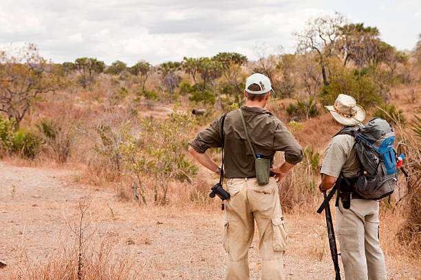 Traveler dressed in neutral safari clothing with a Tanzania safari guide observing an elephant during a walking safari in Selous Game Reserve