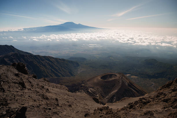 13-Day Mount Meru & Kilimanjaro Combo Cost – Mount Meru and Kilimanjaro, Mount Meru crater with Mount Kilimanjaro in the background under a cloudy sky, Tanzania