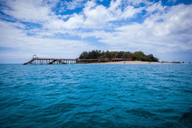 View of Prison Island in Zanzibar and its wooden pier from a boat on turquoise Indian Ocean waters