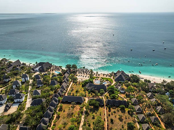 Royal Zanzibar Beach Resort: Nungwi beachfront resort in Zanzibar with traditional bungalows, pools and sun loungers opening onto turquoise Indian Ocean waters dotted with boats under a bright sky