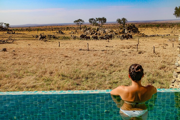 Guest swimming with elephants visible in the distance at Four Seasons Safari Lodge Serengeti