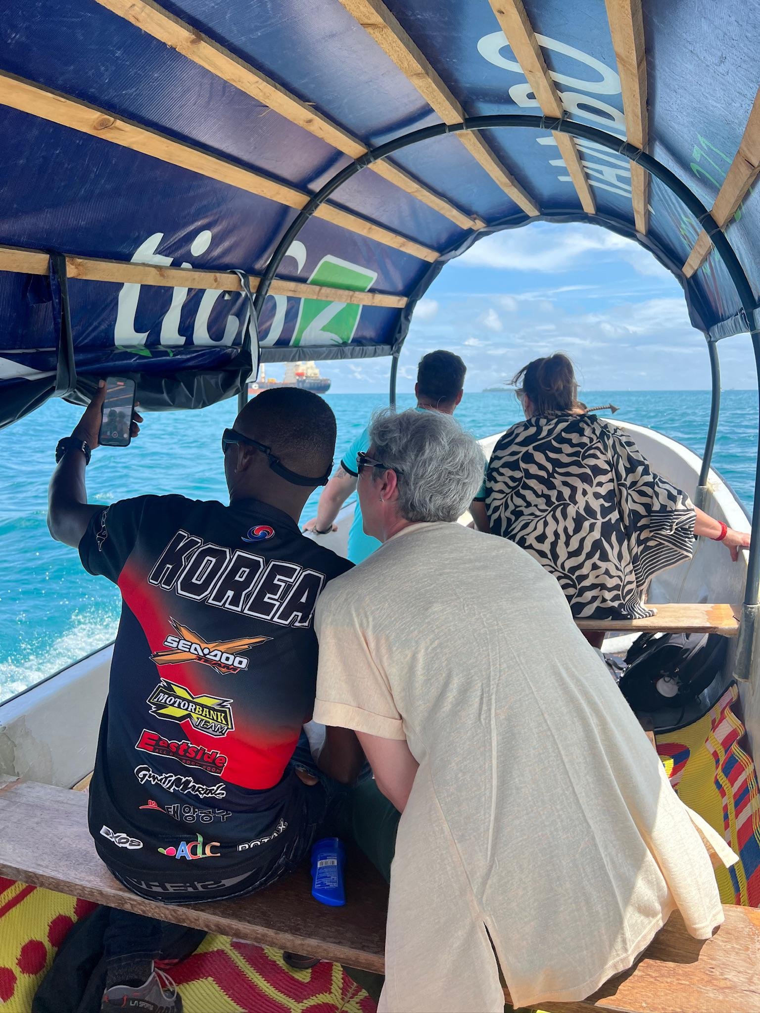 Travellers sailing on a traditional dhow in the Indian Ocean off Zanzibar